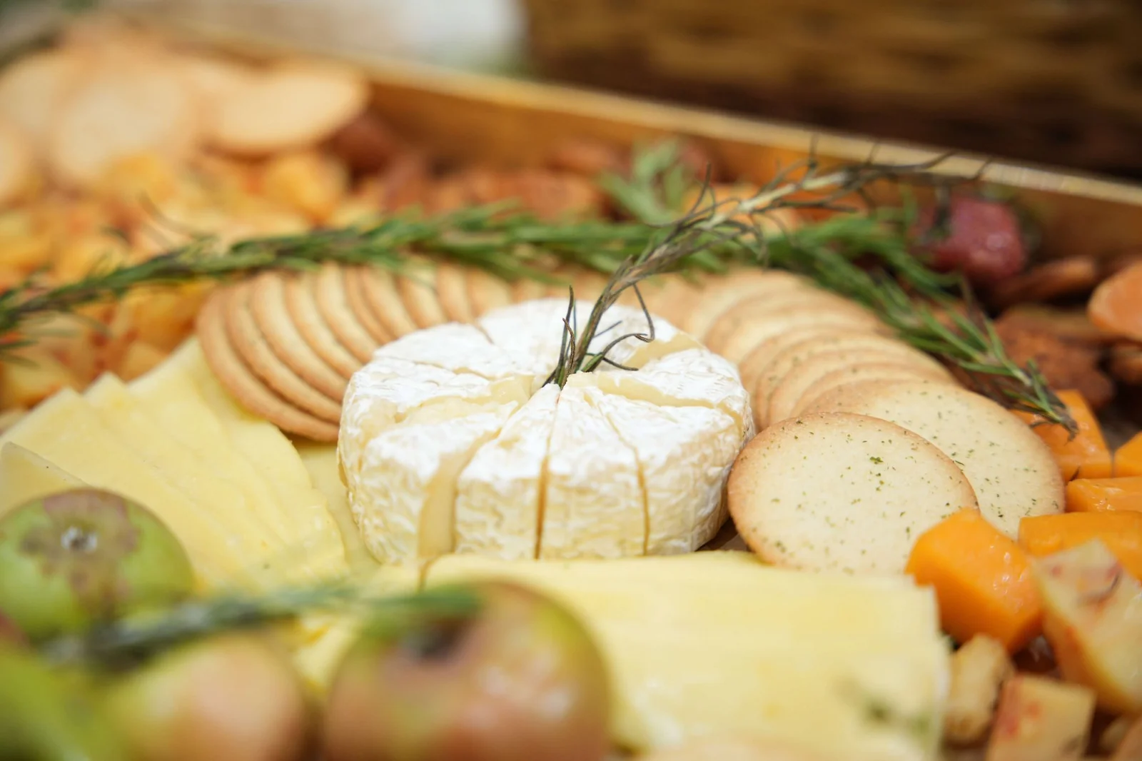 A close-up of cheeses, crackers and fruit on the grazing board.