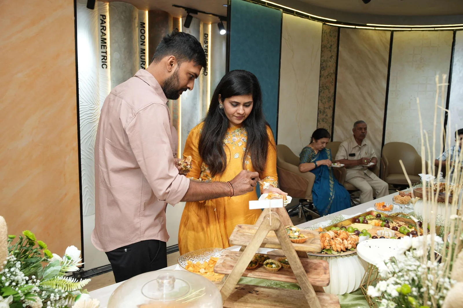 Two guests helping themselves to food from tiered serving stands.