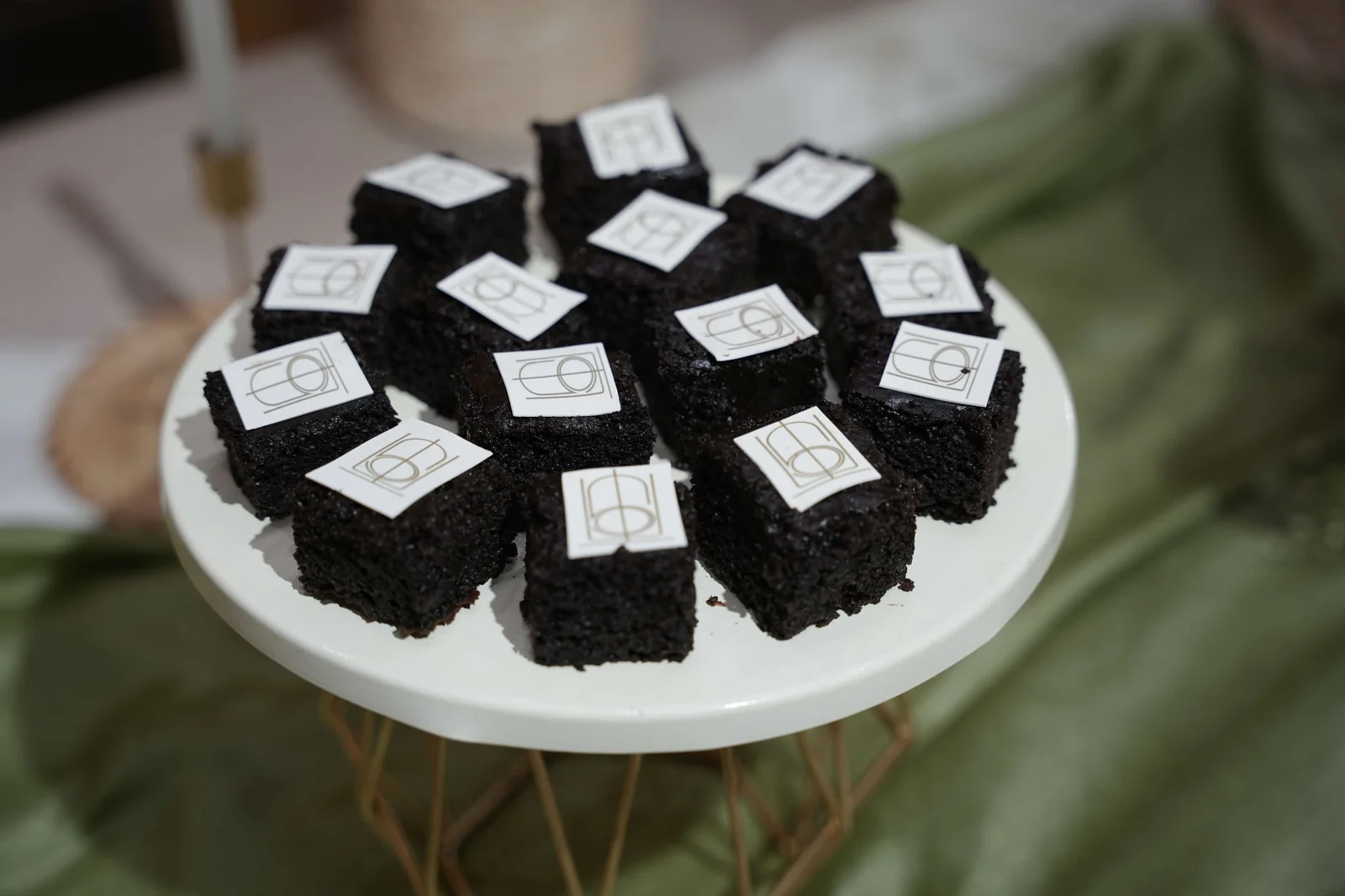 Small dark-coloured sweet treats with decorative toppers on a raised serving plate.